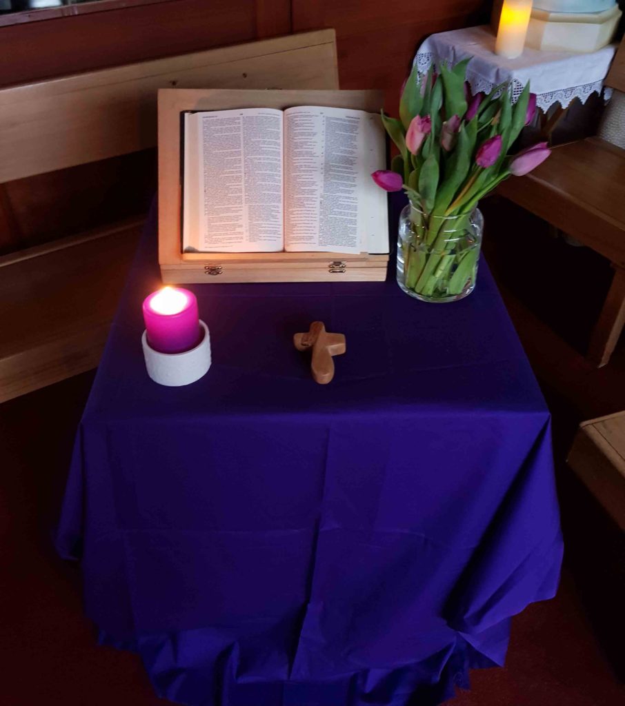 Bible candle and flowers on a blue table cloth